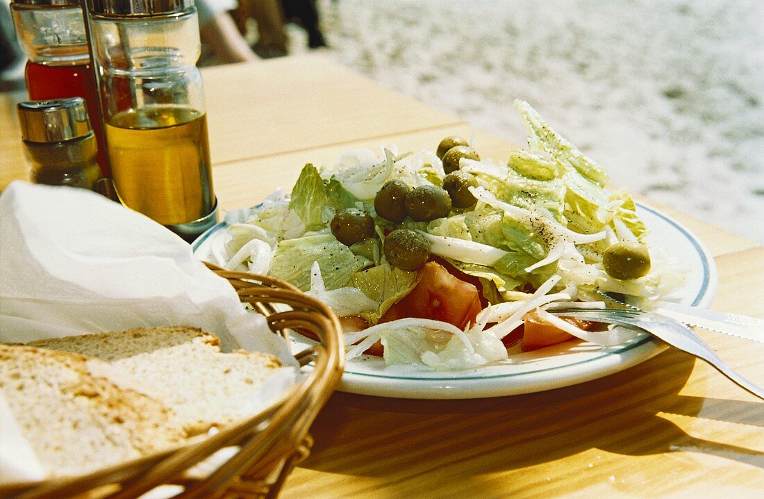 Griechischer Salat mit Bauernbrot auf Tisch im Freien