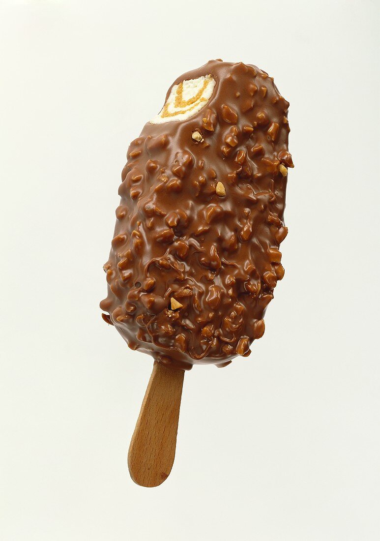 Chocolate-coated ice cream with nuts on stick