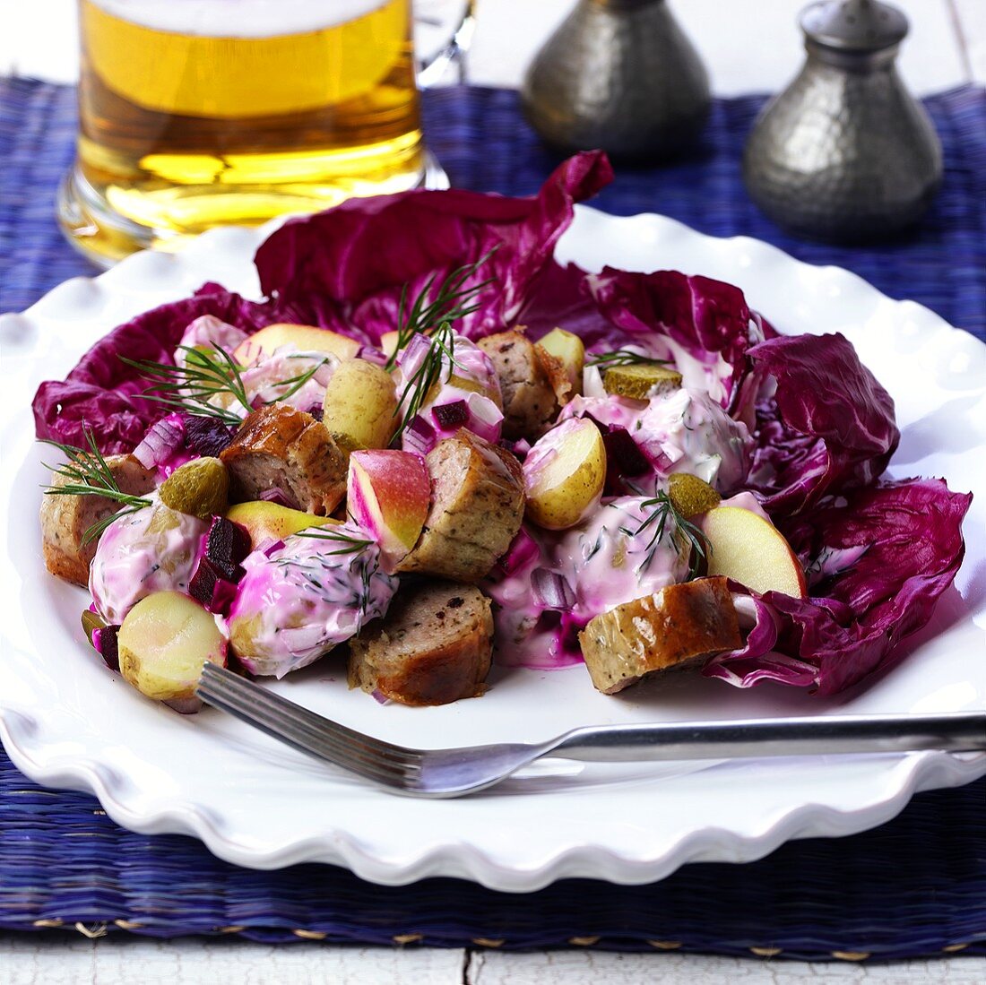 Potato salad with sausages and red cabbage leaves