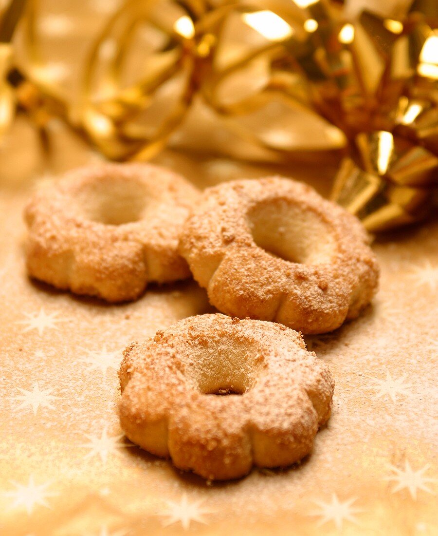 Three Christmas biscuits in front of gold decoration