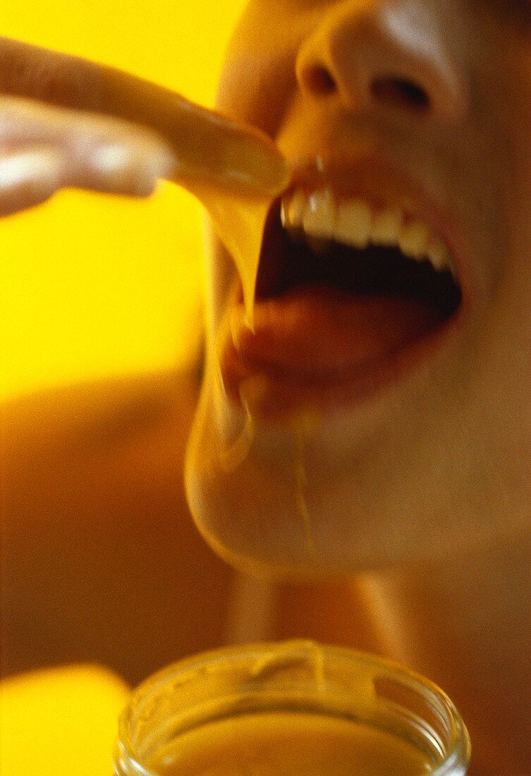 Frau isst Honig mit Finger