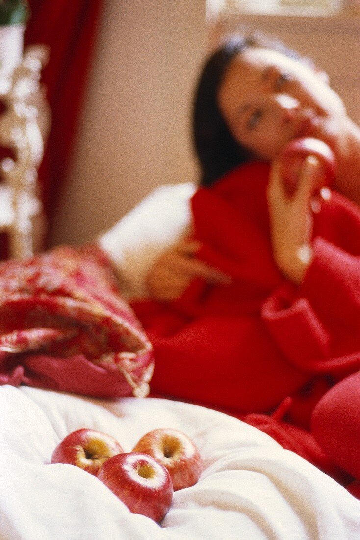 Junge Frau im roten Bademantel mit frischen Äpfeln