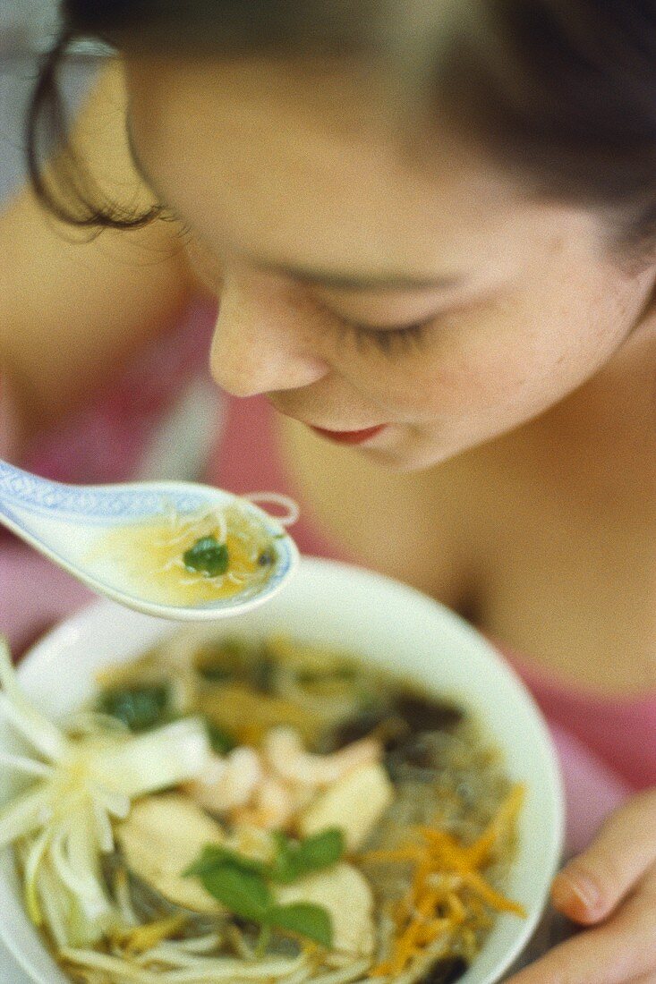 Woman eating Asian glass noodle soup