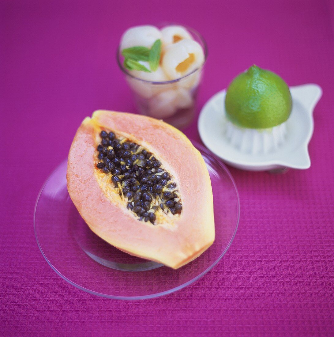 Halbe Papaya; Lychees; Limette auf Zitruspresse