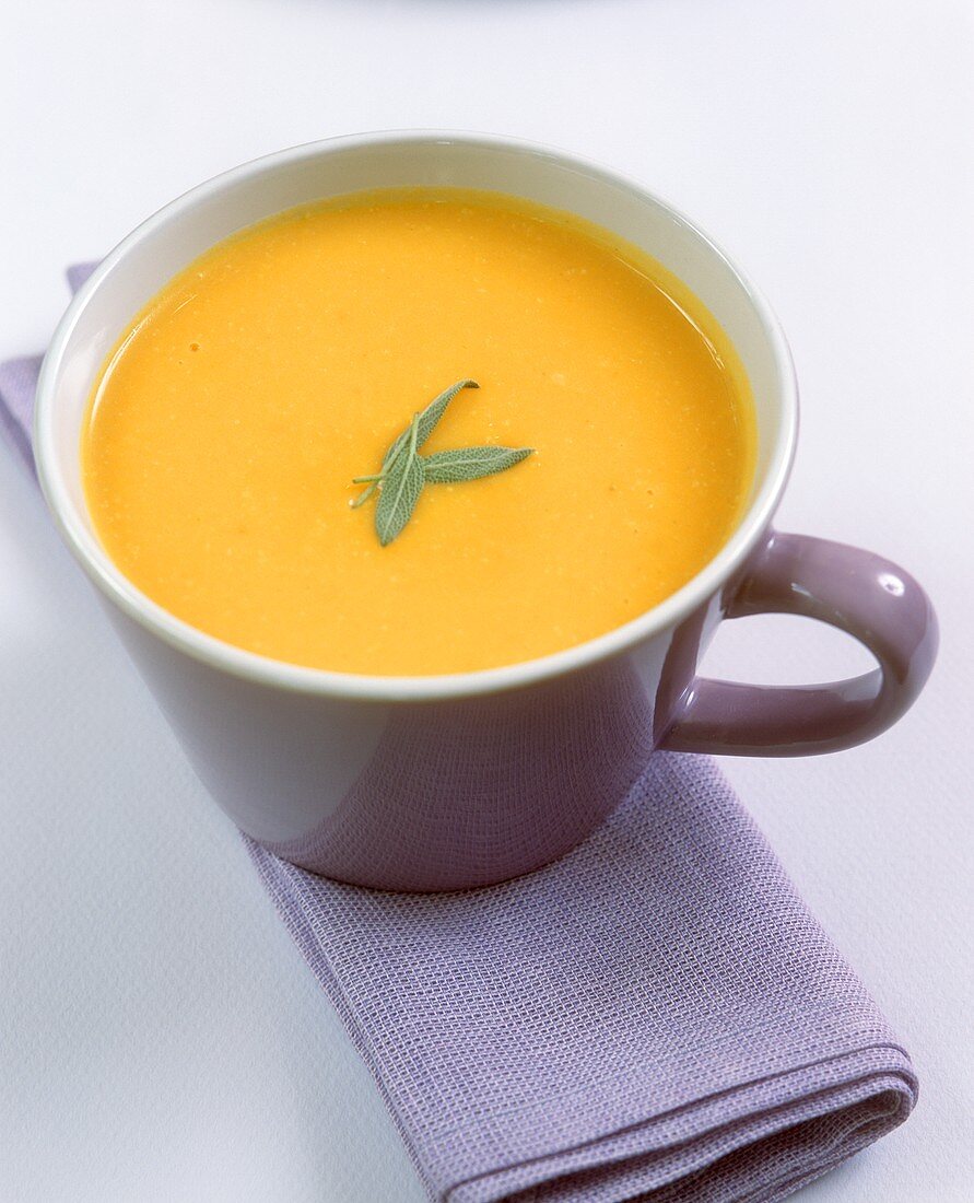 Kürbissuppe mit Salbeiblättchen in einer Tasse serviert