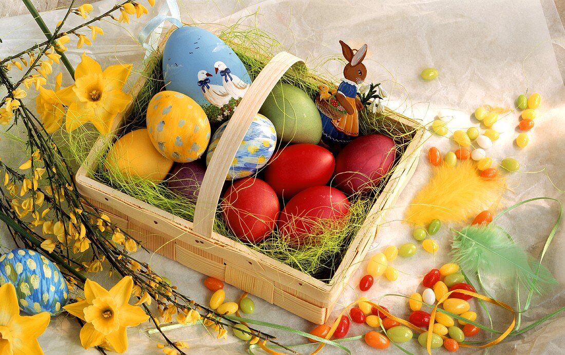 Coloured Easter eggs in chip basket; sugar eggs; spring flowers