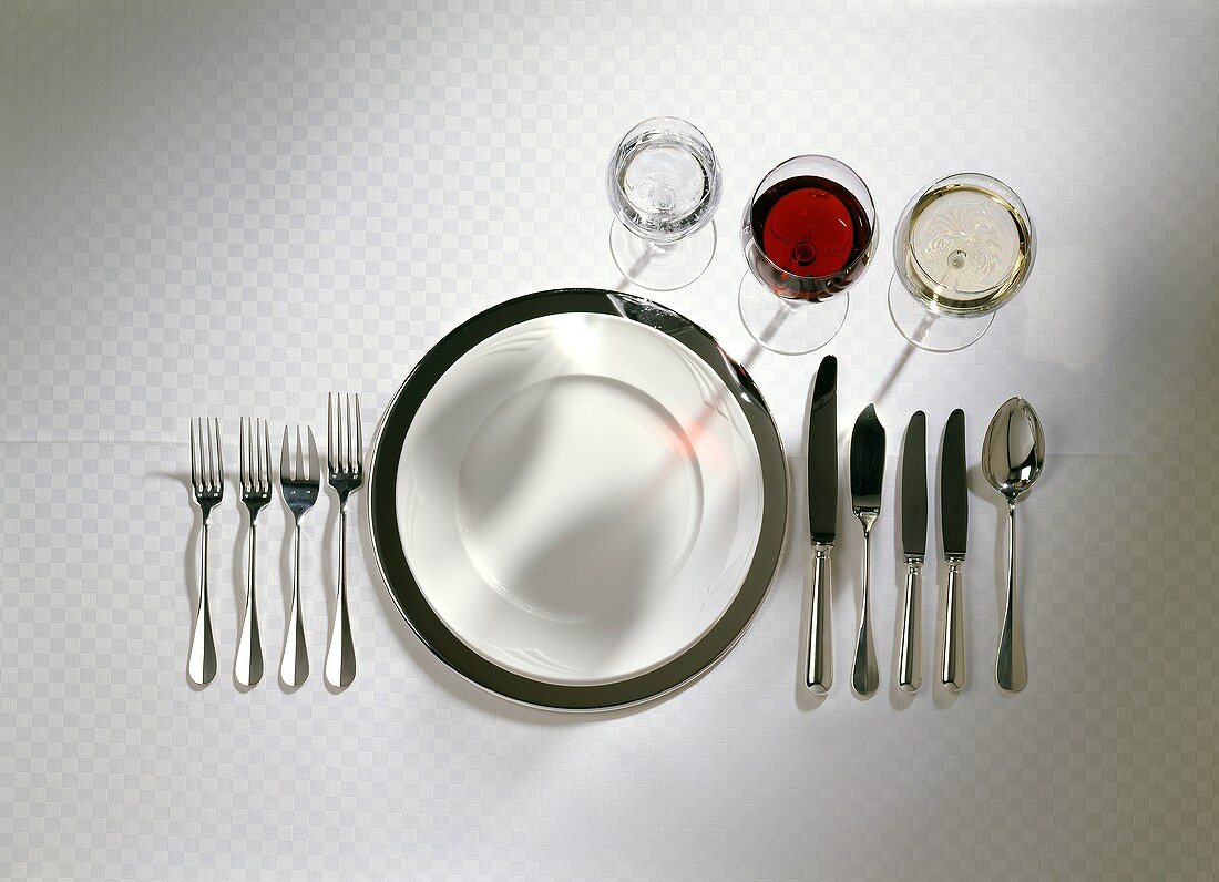 Setting for meal with several courses: cutlery, wine glasses