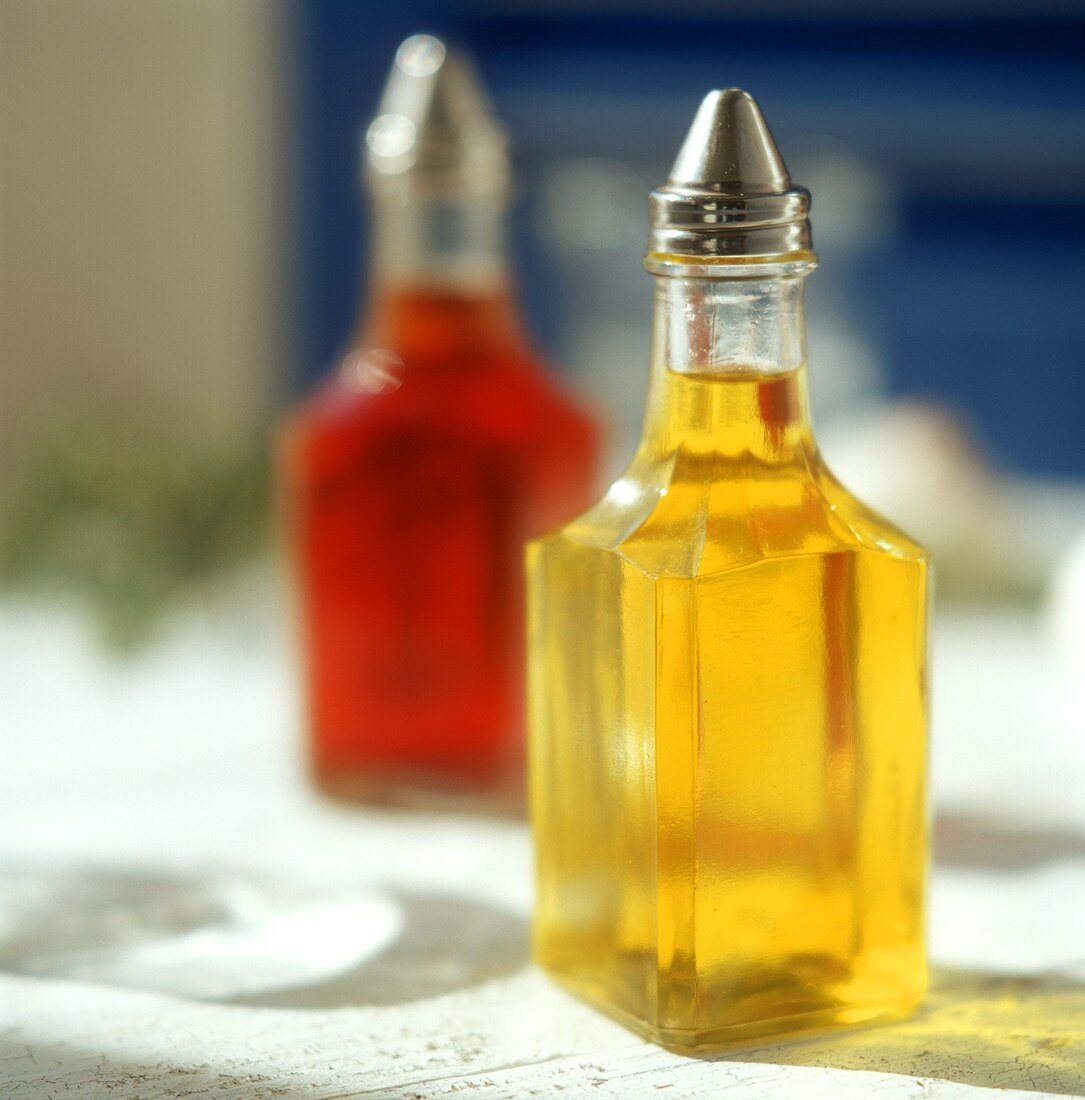 Olivenöl und Rotweinessig in Fläschchen auf Tisch