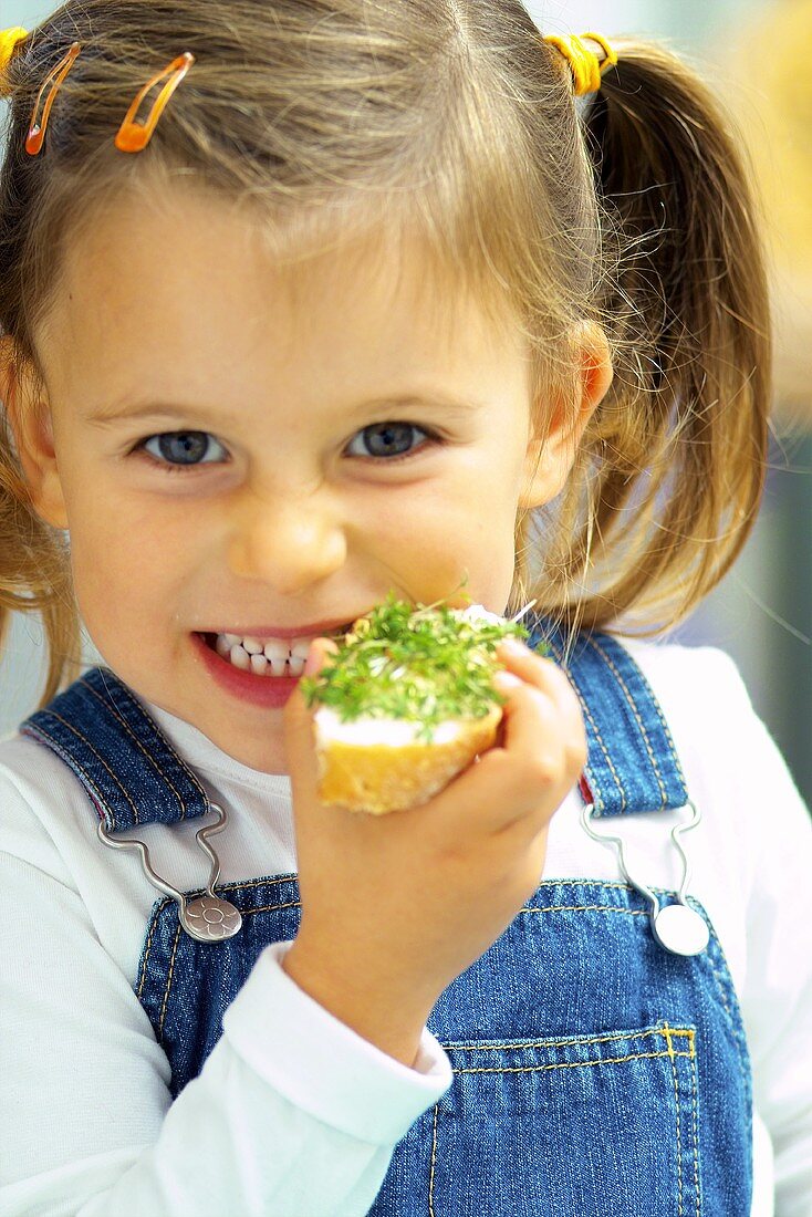 Kleines Mädchen isst Kressebrot