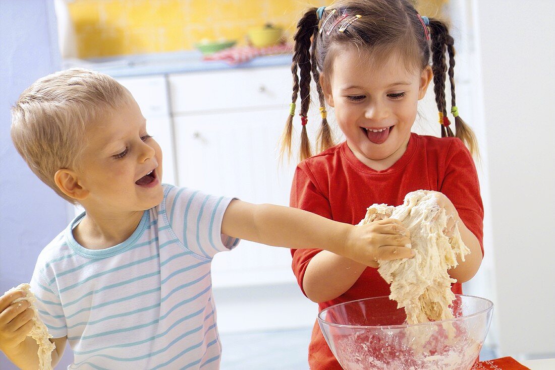 Mädchen und kleiner Junge kneten Pizzateig