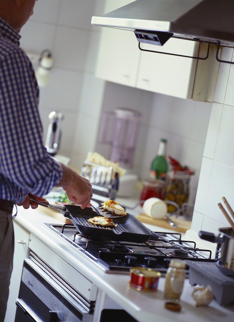 Man frying meat in kitchen