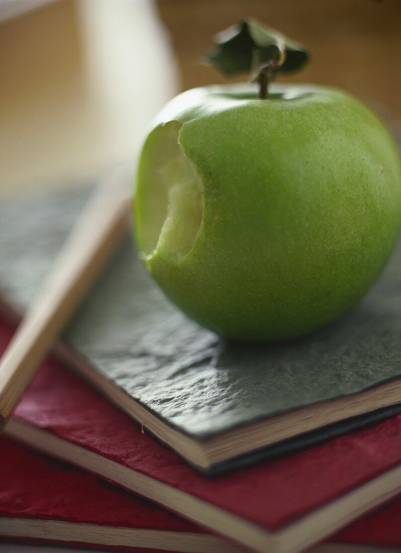 Green apple with a bite taken, on school exercise books