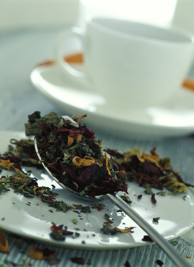 Tea leaves on spoon in front of teacup