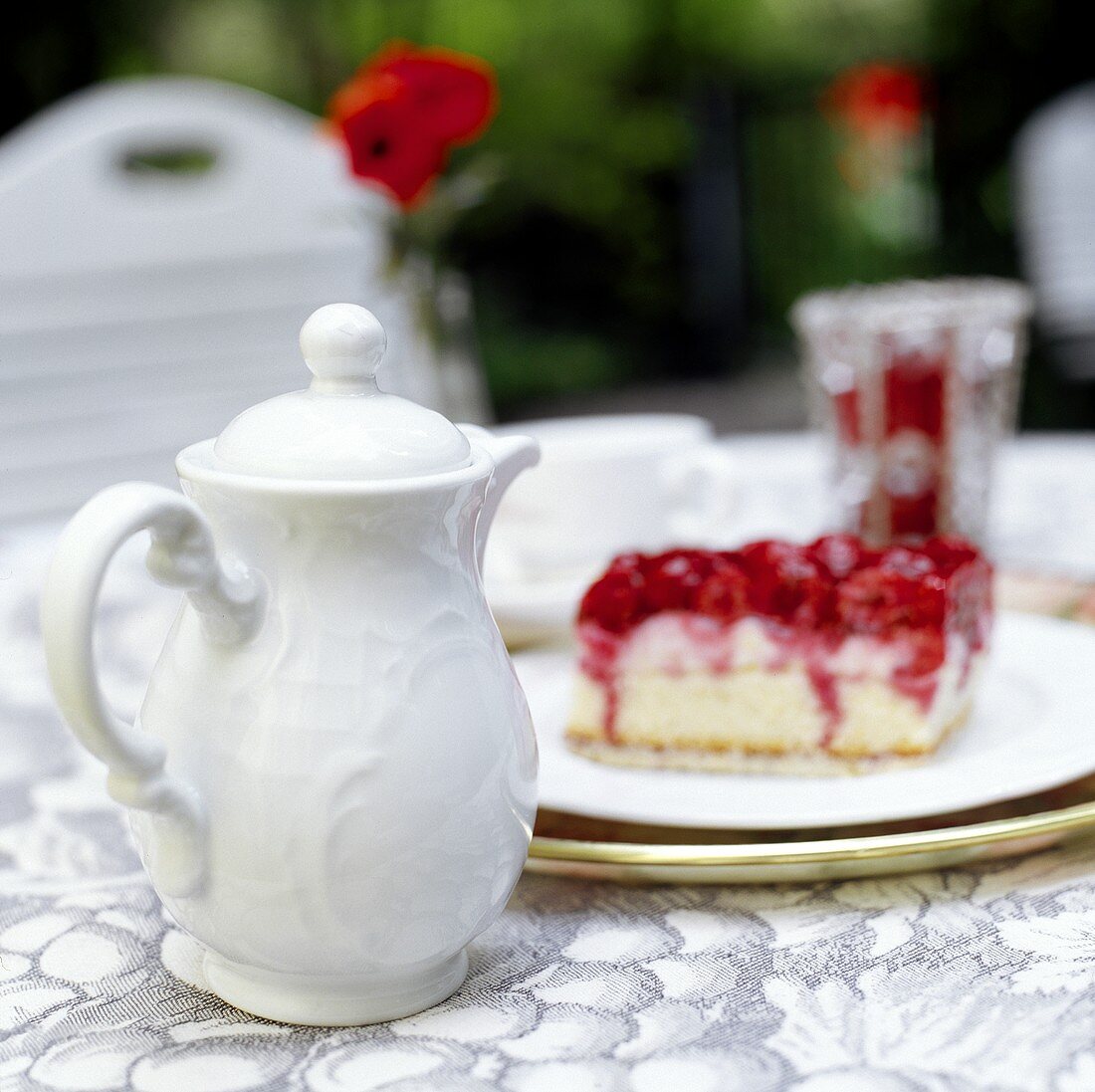 weiße Kaffeekanne und Stück Kuchen auf Tisch im Freien