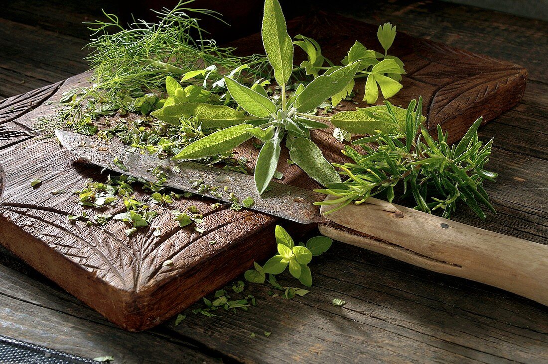 Fresh herbs on wooden chopping board with old knife