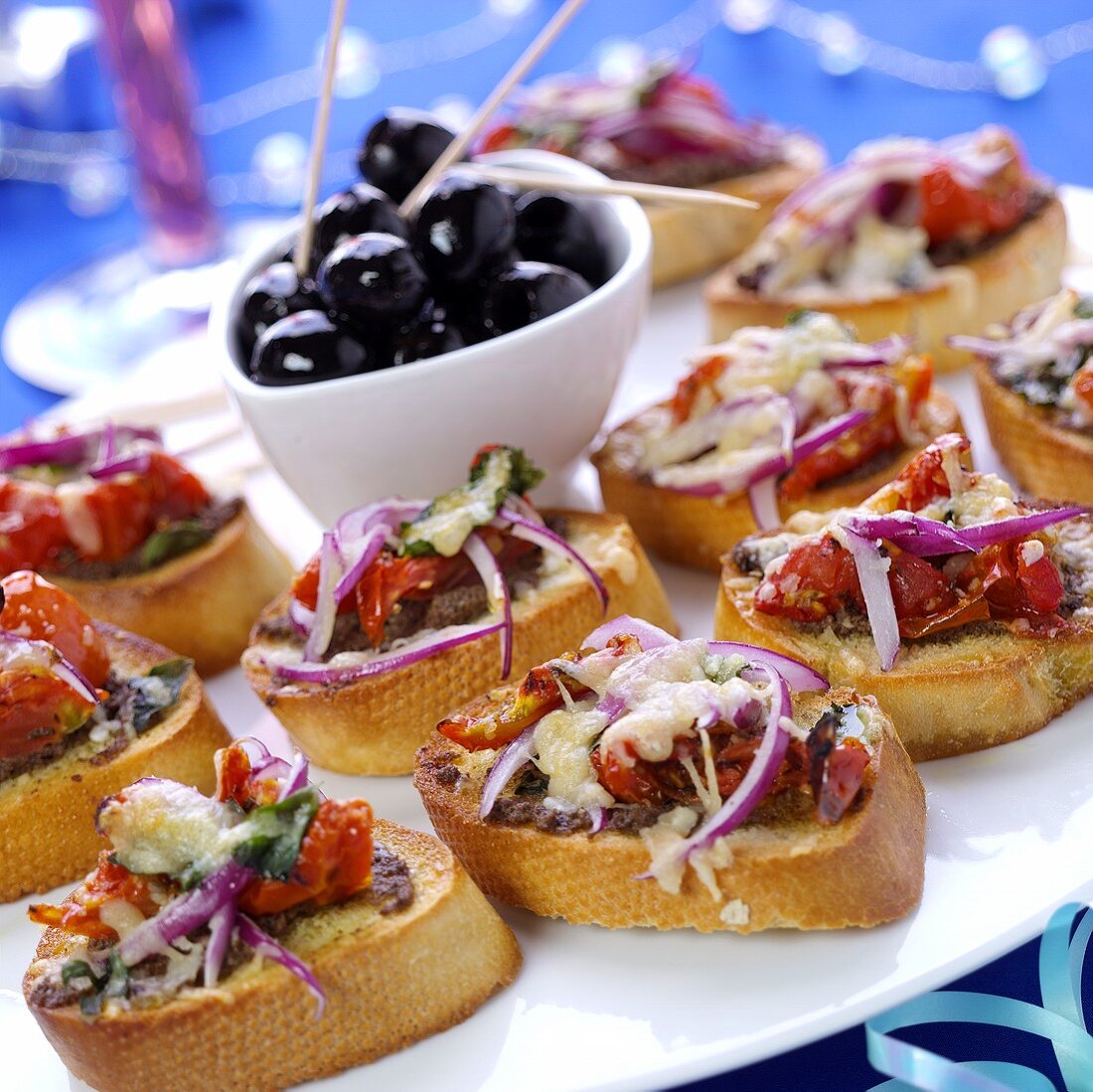 Crostini with toasted cheese and tomatoes; olives