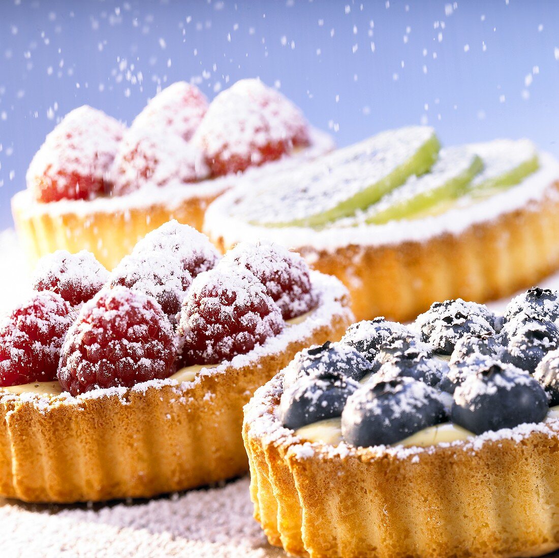 Assorted small fruit flans with icing sugar
