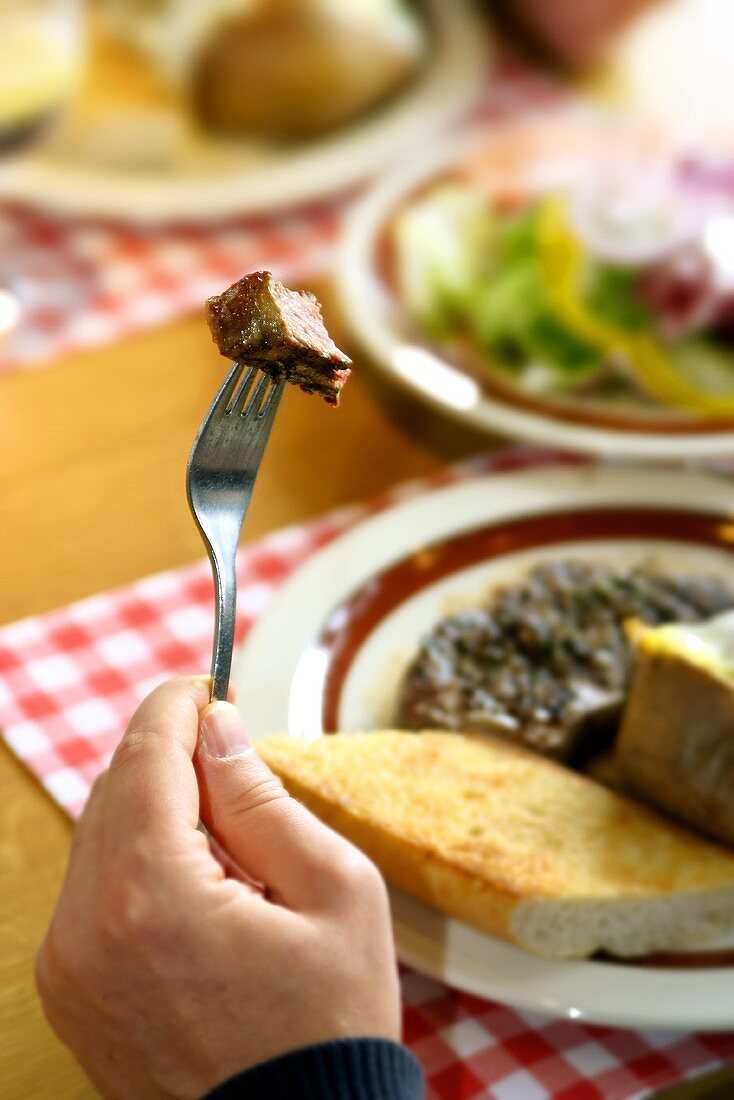 Piece of steak on fork in restaurant