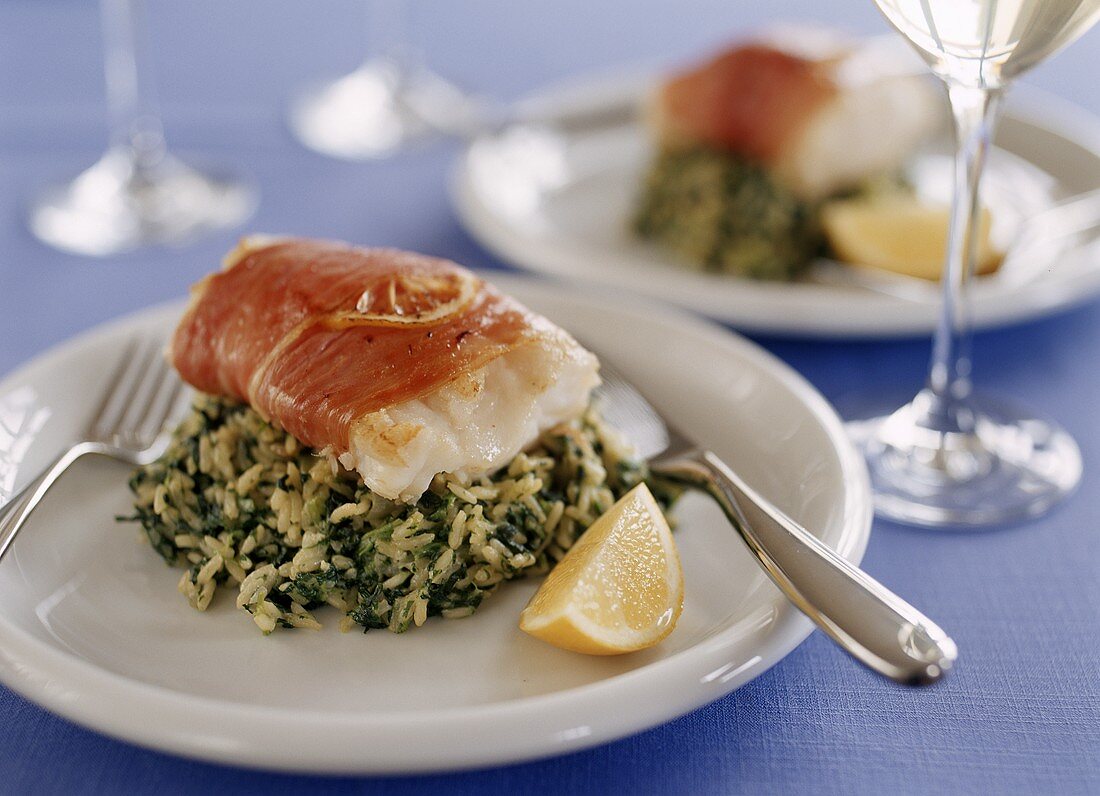 Cod wrapped in ham on rice with herbs