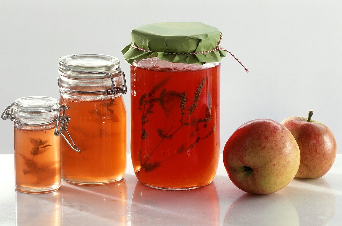 Three jars of apple jelly and two apples