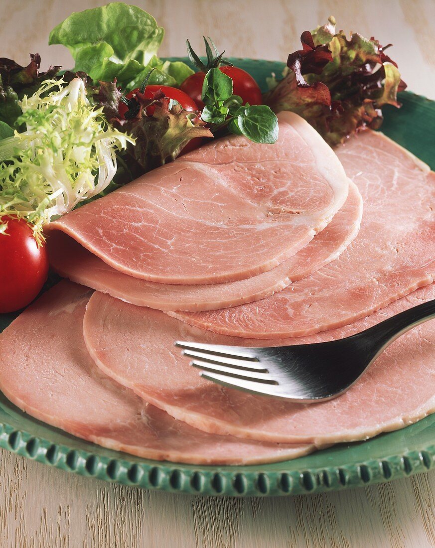 Sliced boiled ham with salad on plate