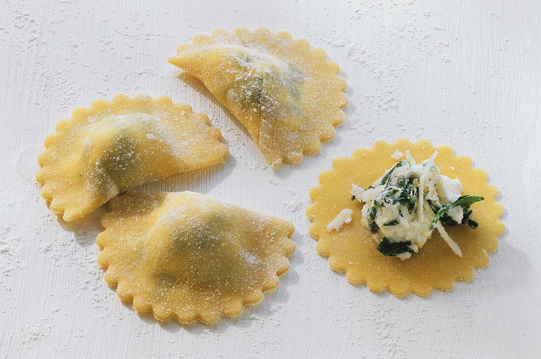 Home-made ravioli with filling on wooden board