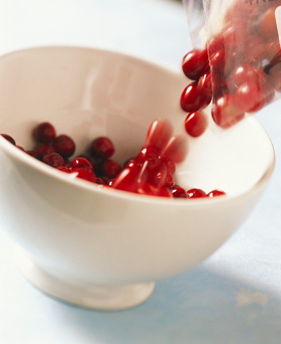 Cranberries being transferred from package into a bowl