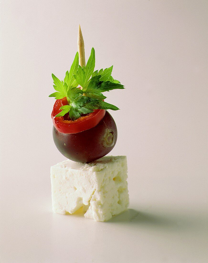 A cocktail stick with sheep's cheese and a grape