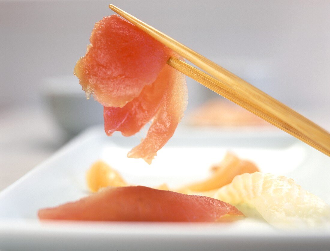 Ein Stück roher Fisch auf Stäbchen (Sashimi-Sushi)