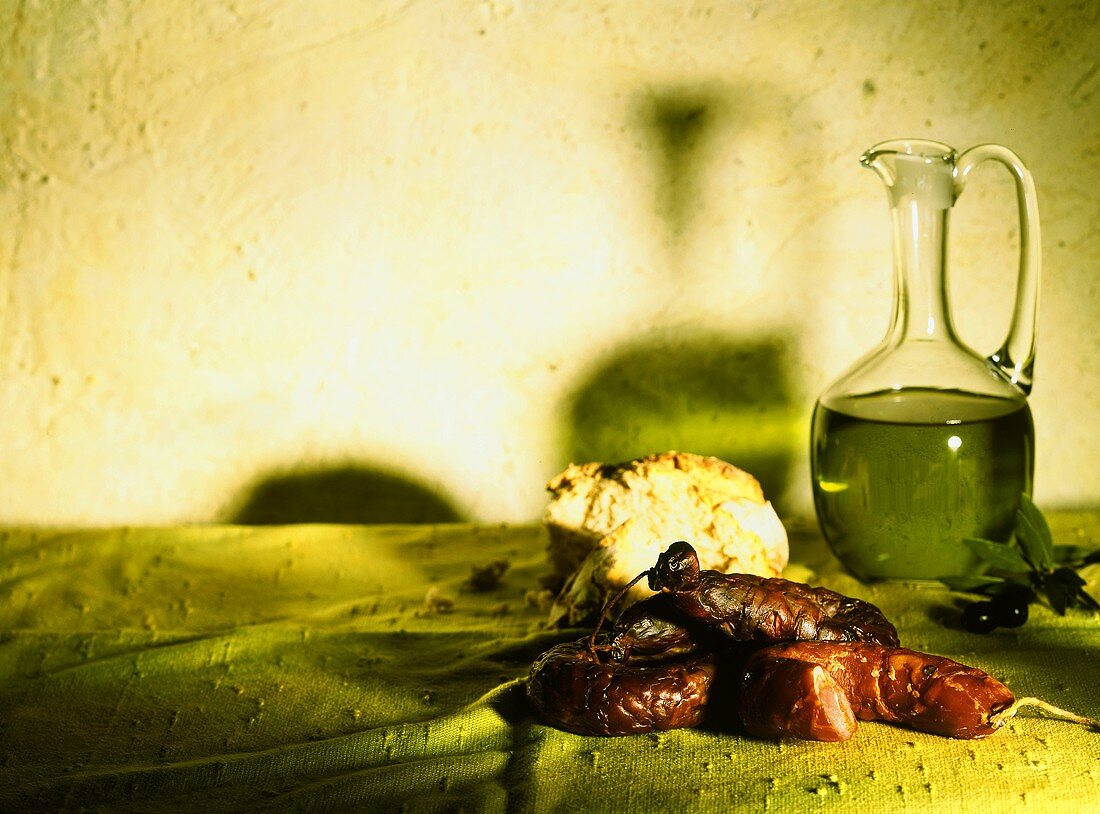 Geräucherte Wurst mit Brot und Olivenöl in einer Kanne