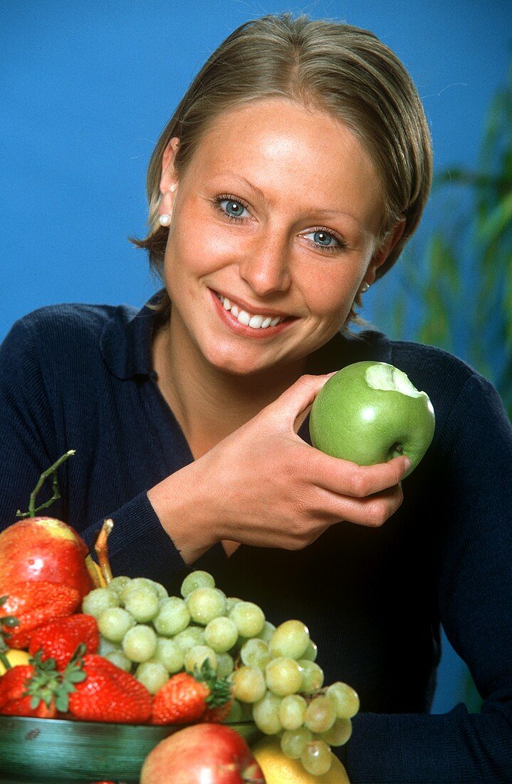 Junge Frau hält einen angebissenen grünen Apfel