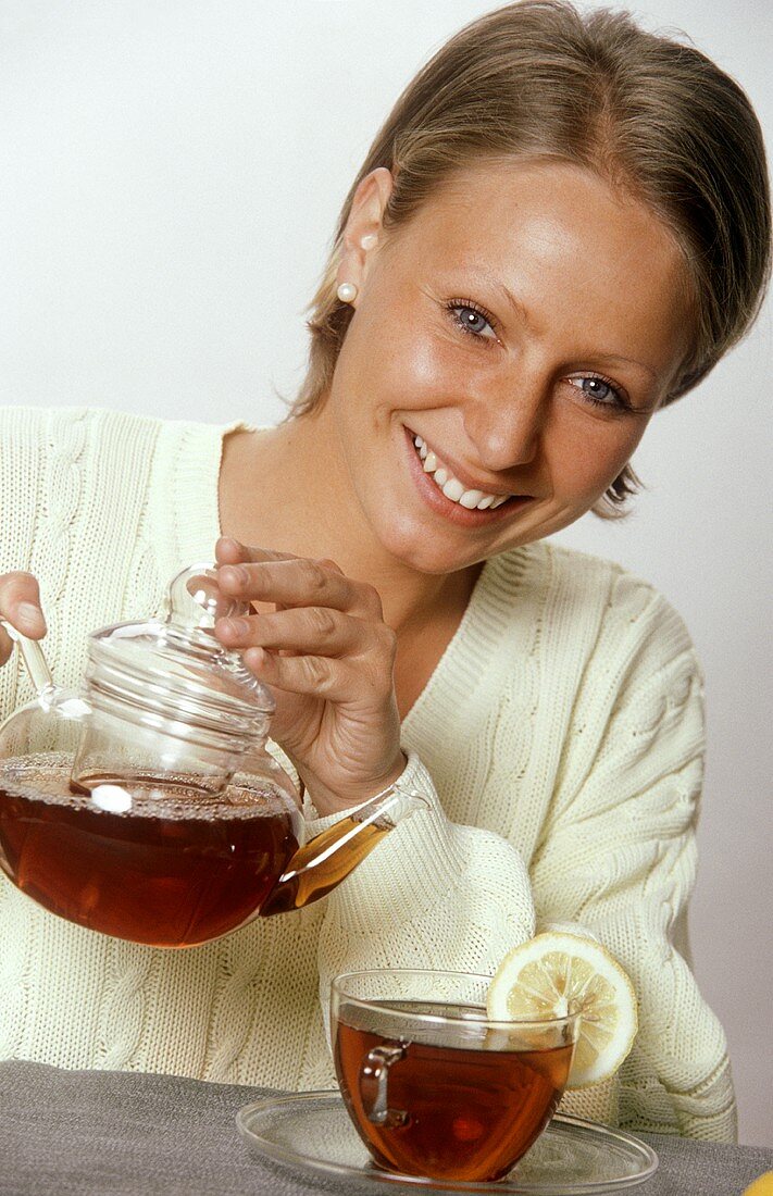 Woman Holding Pot of Tea; Cup of Tea with Lemon