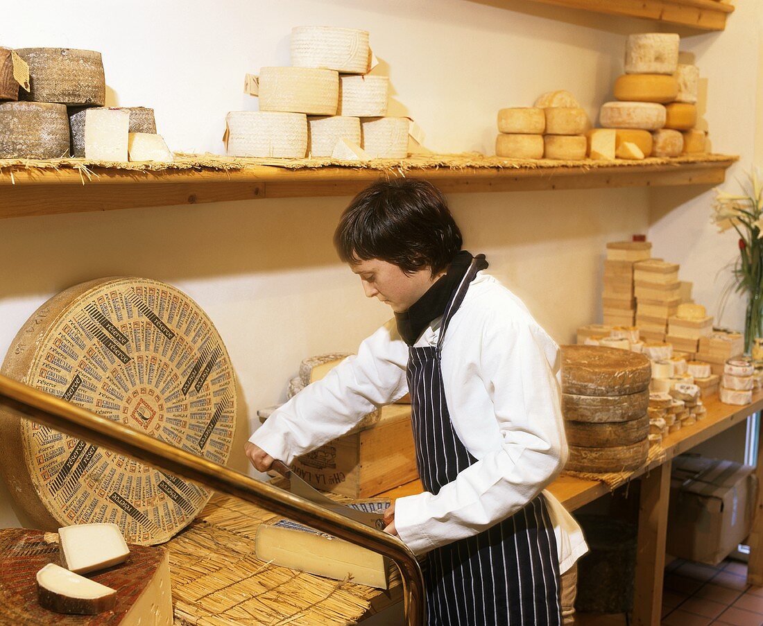 Frau schneidet Käse im Käseladen