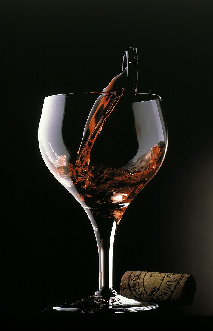 Rotwein wird in ein Glas eingeschenkt