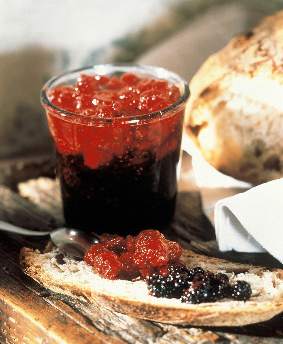 Blackberry and raspberry jam in a jar and on bread
