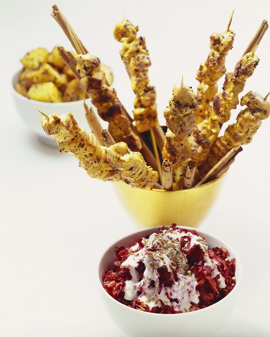 Sate sticks, beetroot salad and fried potatoes in bowls