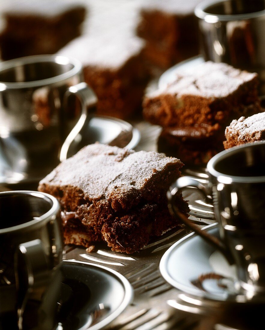 Schokoladenkuchen in Schnitten und Kaffeetassen