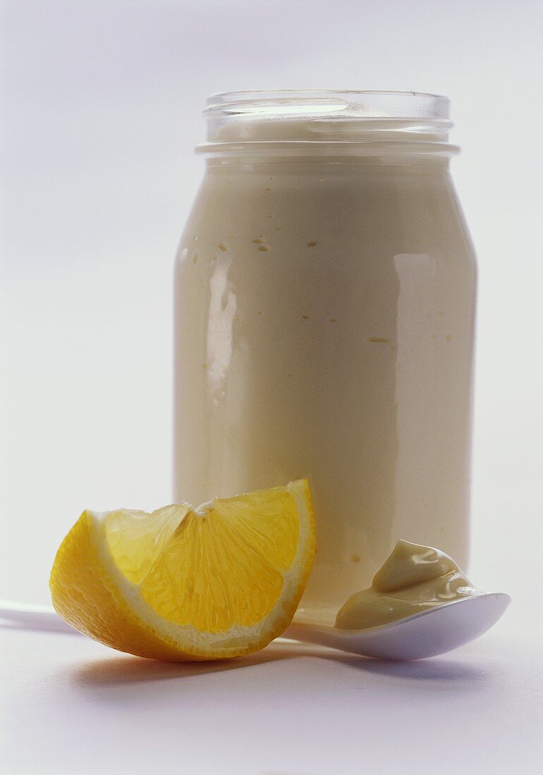 Mayonnaise im Glas und auf Löffel; Zitrone