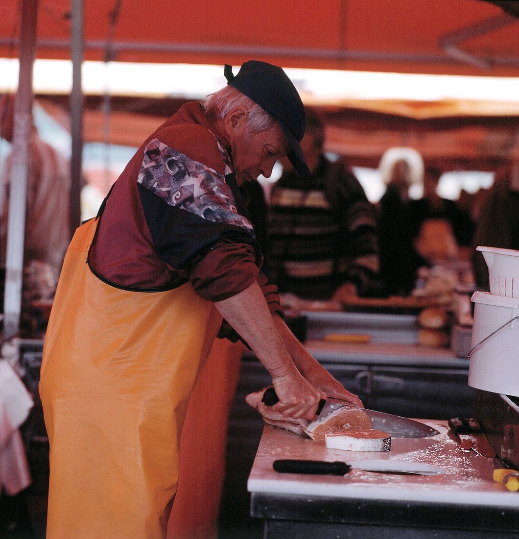 Mann schneidet Lachs in Scheiben; Fischmarkt, Norwegen