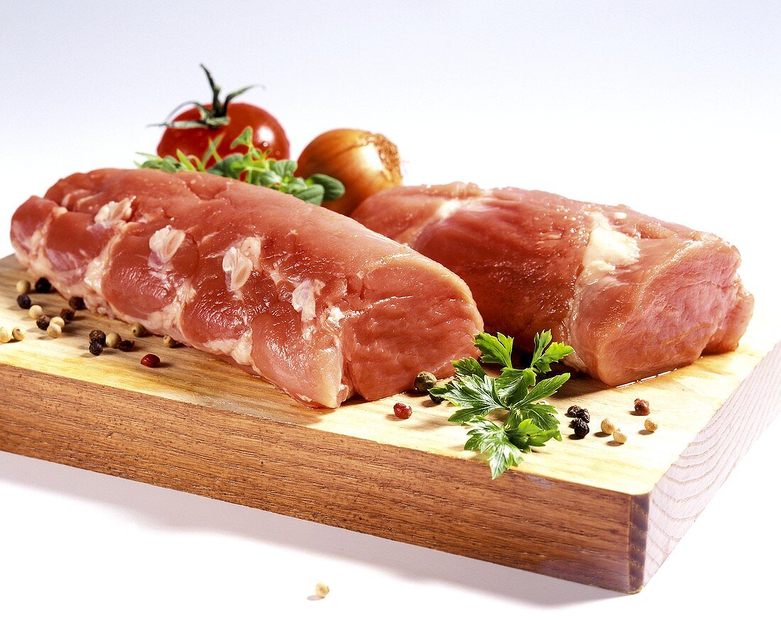 Pork Tenderloin on a Cutting Board with Herbs and Peppercorns