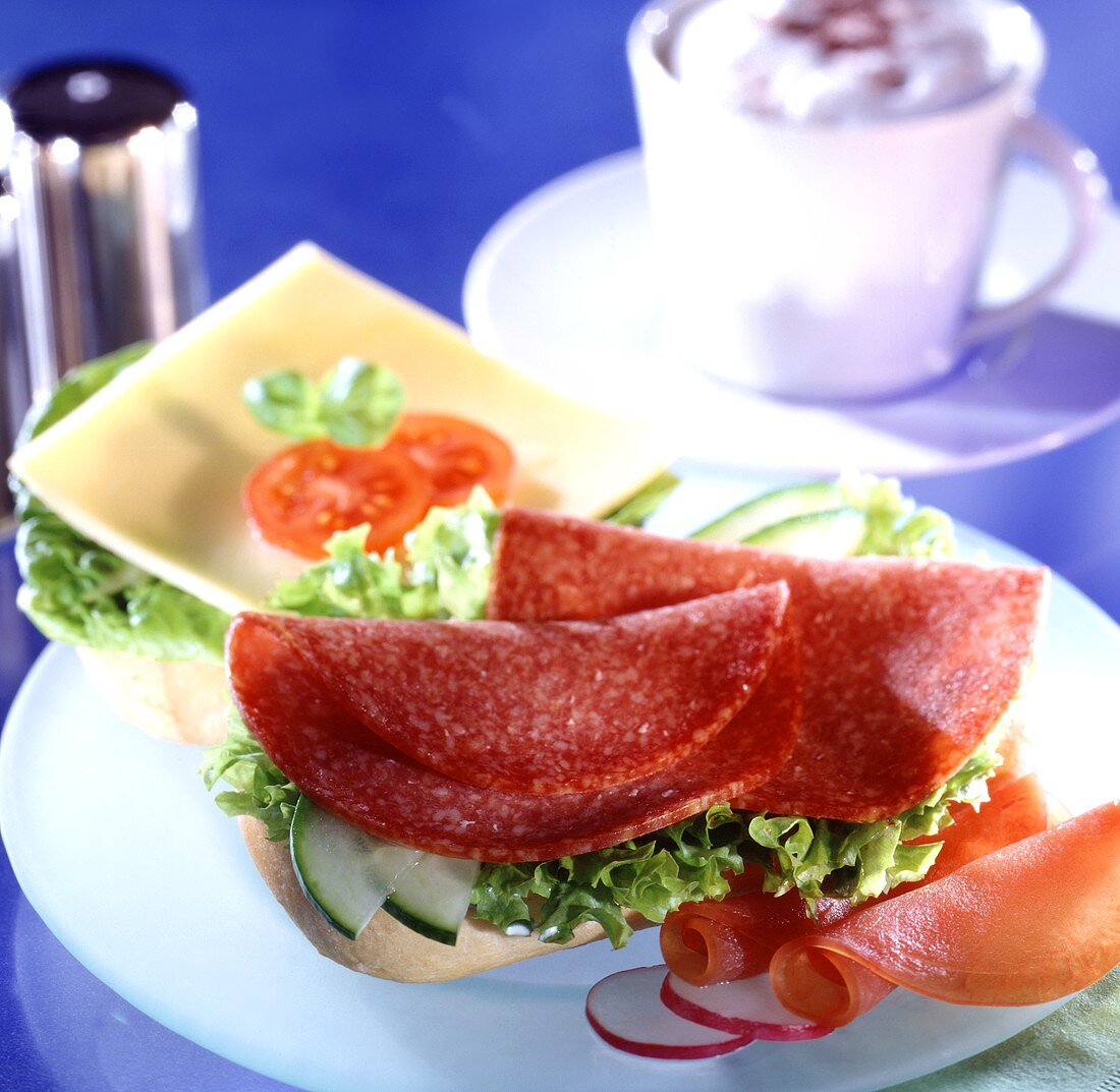 Rolls topped with salami and cheese; coffee cup