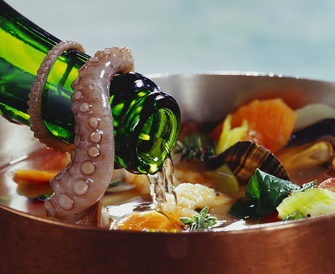 Pouring wine into seafood soup