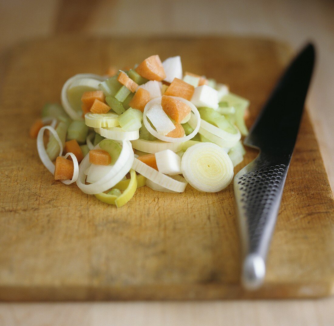 Chopped soup vegetables on chopping board with knife