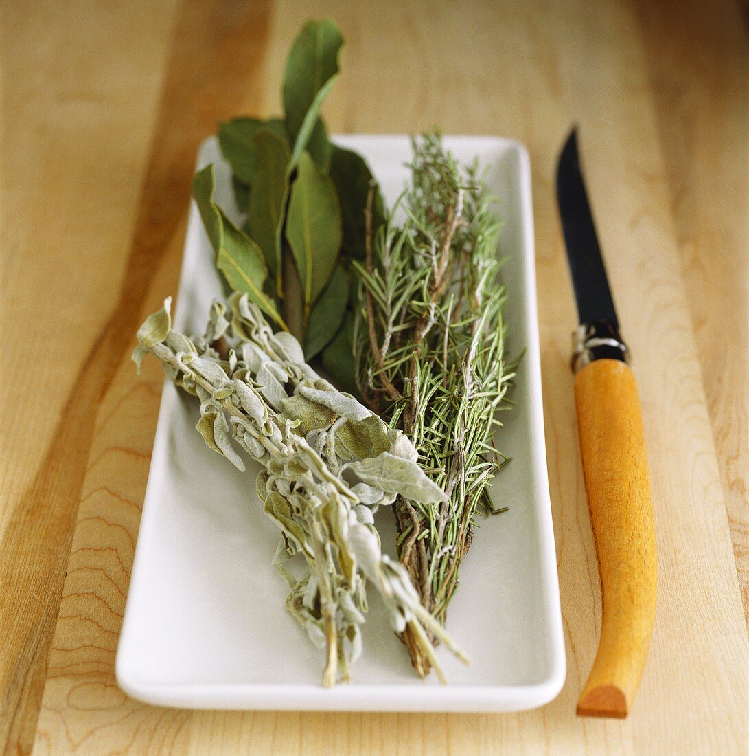 Dried herbs: rosemary, sage and bay; knife
