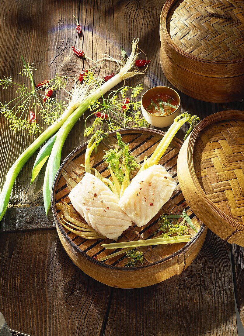 Steamed fish with leeks and dill in bamboo basket