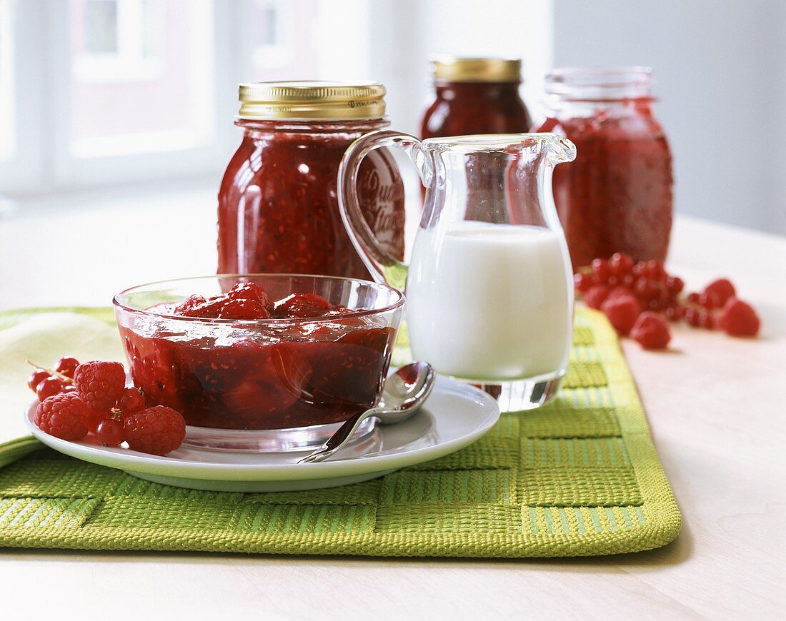 Berry jam in glass bowl and preserving jar; milk jug