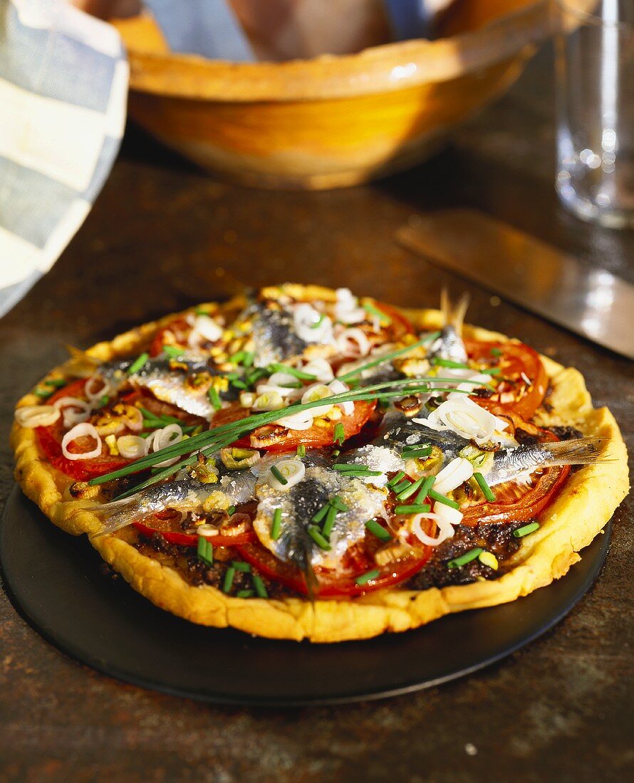 Pizza with sardines, tomatoes and spring onions