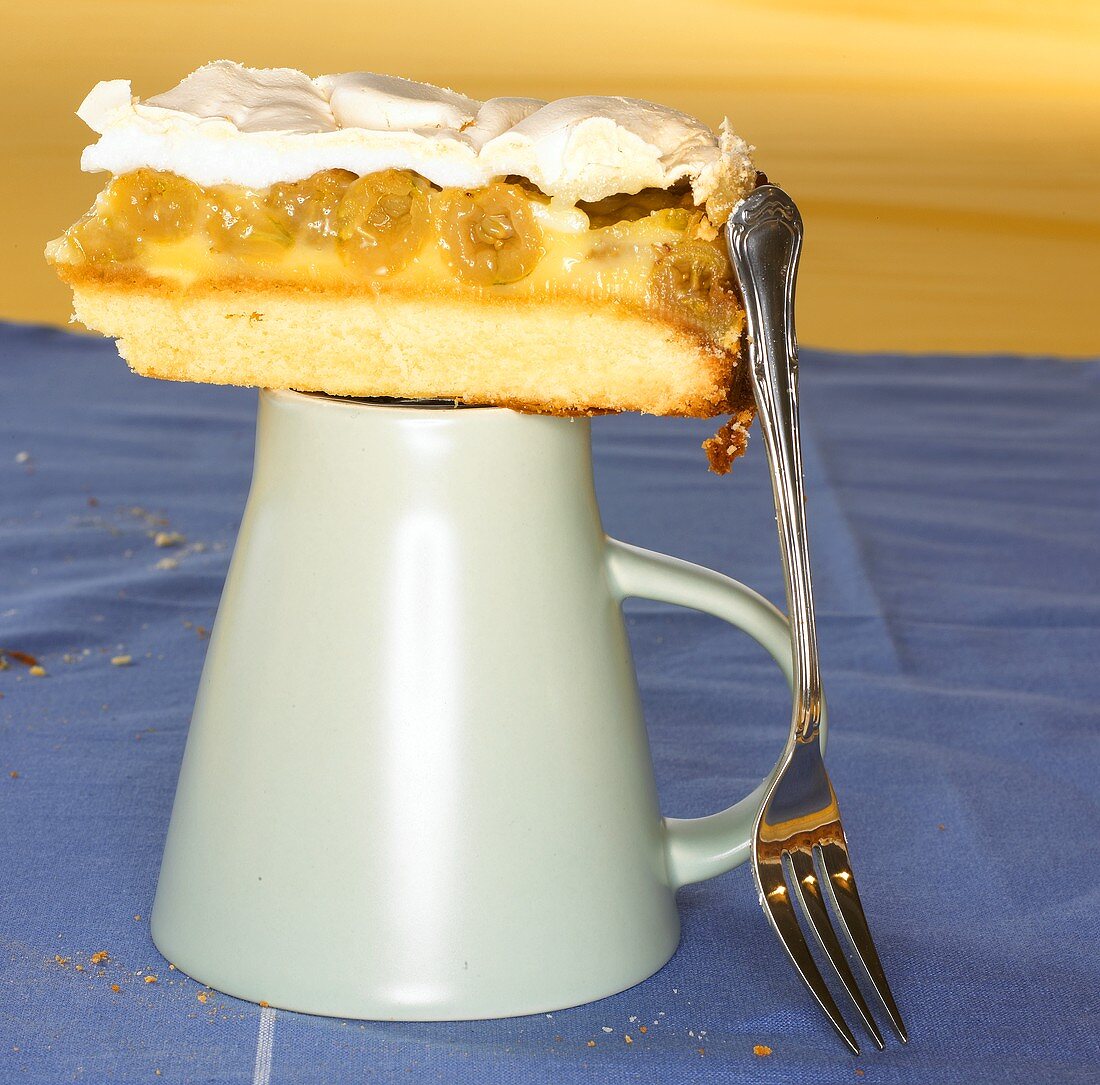 Stück Stachelbeerkuchen mit Baiser auf umgedrehter Tasse