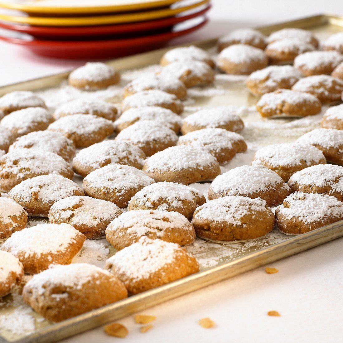 Gingerbread biscuits with icing sugar on baking tray; plate