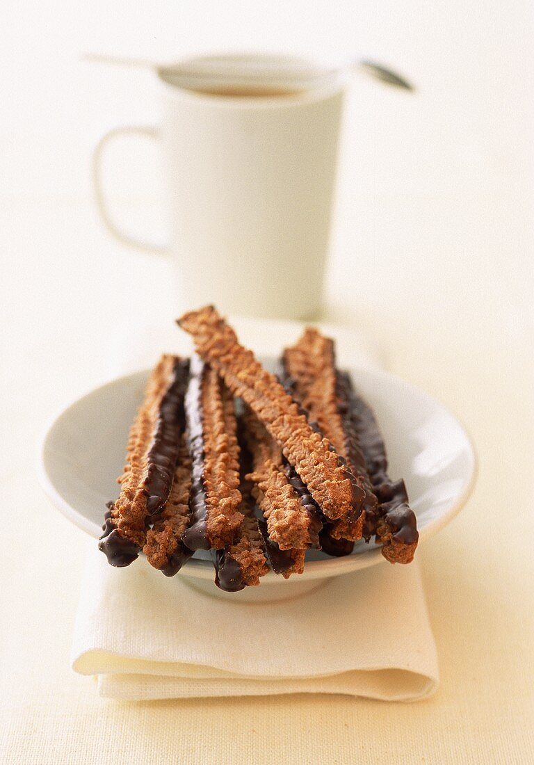 Chocolate sticks on plate in front of coffee cup
